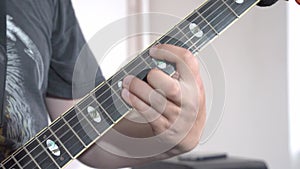 Man hand clamps strings on neck of electric vintage guitar, plays heavy metal.