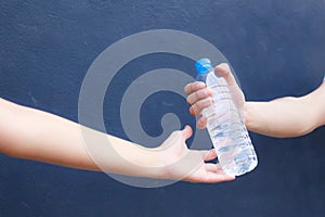 Man hand clean plastic bottle full of fresh drinking water to woman on background