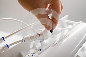 Man hand connect tubes in osmosis water purification filter for home use