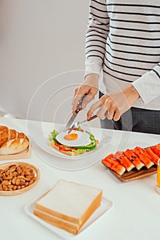 Man hand cutting fried egg on toast is cut with a knife