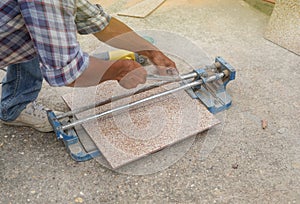 Man hand cutting a tileby using a tile cutter on the floor