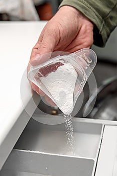 Man hand filling detergent in the washing machine, concept housekeeper