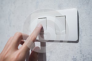 Man hand with finger on light switch.