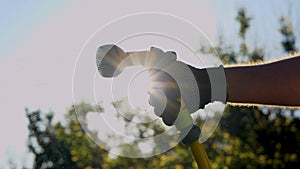 Man hand with garden hose with sprinkler spraying water on green lawn in sunlight. Water flows from hose. Shiny water