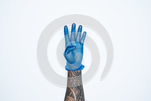 A man hand and gestures in Blue rubber glove shows foue fingers sign isolated on white background