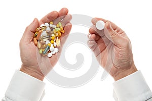 Man hand getting one pill from handful of pills, tablets, vitamins, drugs, capsules isolated on white background. White shirt,