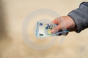 Man hand giving money like a bribe or tips. Holding EURO banknotes on a blurred background, EURO currency