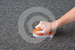 Man hand without gloves cleaning gray  carpet with brush. dry cleaning technique