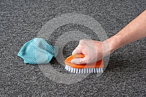 Man hand without gloves cleaning gray  carpet with brush and microfibre cloth. dry cleaning technique