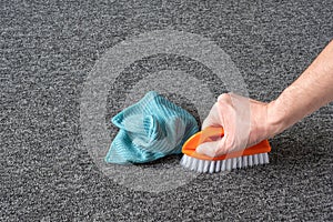 Man hand without gloves cleaning gray  carpet with brush and microfibre cloth. dry cleaning technique photo