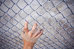 Man hand grabbing steel mesh cage. no freedom.