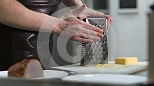 Man hand grating yellow cheese with a metal grater