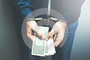 Man hand handcuffs and money on dark background