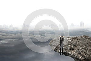 Man hand hanging on cliff with gray cloudy sky cityscape