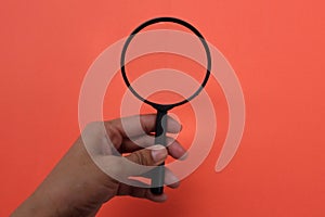 Man hand hlding magnifying glass on the on a orange background