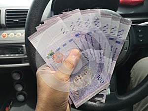 Man hand hold one hundred ringgit malaysia bills.