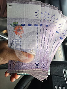 Man hand hold one hundred ringgit malaysia bills.