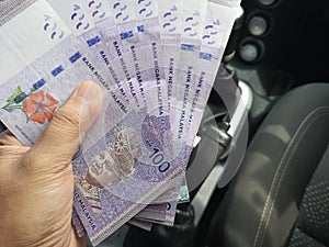 Man hand hold one hundred ringgit malaysia bills.
