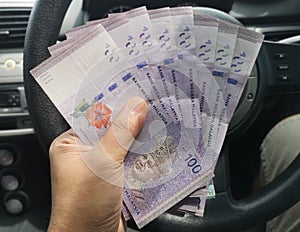 Man hand hold one hundred ringgit malaysia bills.