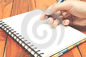 Man hand hold a pen writing on the notebook