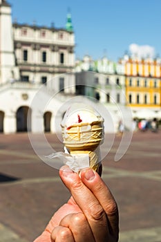 Man hand hold vanilla berry ice cream gelato in a waffle cone on blurred old city background