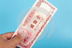 Man hand holding 100 Taiwan dollar bank note with blue background