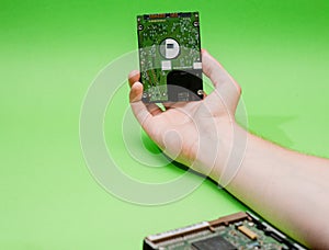 Man hand holding 2.5 HDD on green background. Mining on hard disk drive concept