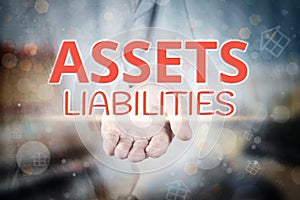 Man hand holding Assets Liabilities text on blurry home icon pro photo