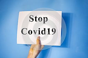 man hand holding blank card paper sheet isolated on blue background with copy space.Holding a sign that says Covid 19