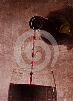 Man hand holding Bottle pouring red wine filling Glass on arty background