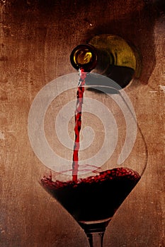 Man hand holding Bottle pouring red wine filling Glass on arty background photo