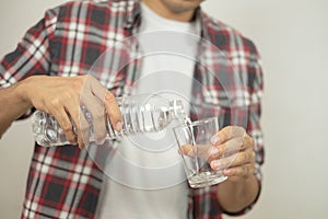 Man hand holding a bottle of water Pouring water into a glass