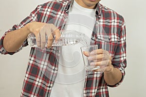 Man hand holding a bottle of water Pouring water into a glass