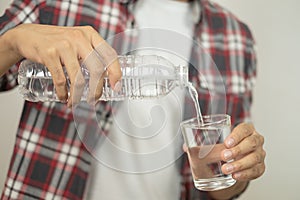 Man hand holding a bottle of water Pouring water into a glass