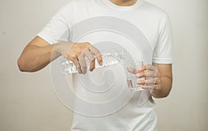 Man hand holding a bottle of water Pouring water into a glass