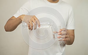 Man hand holding a bottle of water Pouring water into a glass