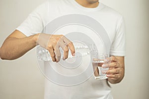 Man hand holding a bottle of water Pouring water into a glass