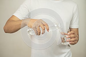 Man hand holding a bottle of water Pouring water into a glass