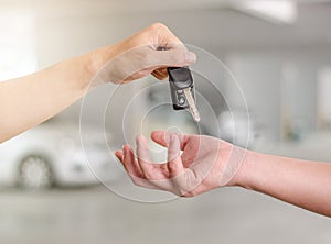 Man hand holding a car key and handing it over to another person