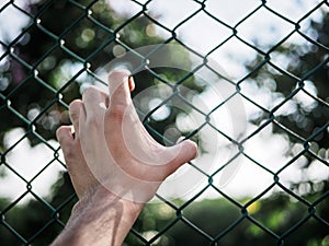Man hand holding on chain link fence to remember Human Rights Da