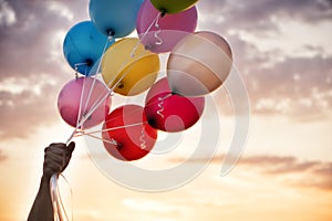 Man Hand Holding Colorful Balloons And A Beautiful Sunset. Birthday Party Balloons