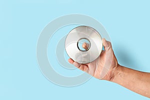 Man hand holding a compact disc on a blue background