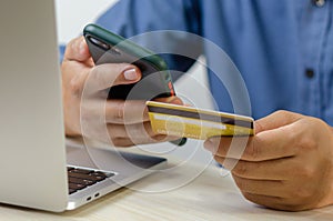 Man hand holding credit card and mobile smart phone with computer laptop.Business finance banking internet and shopping online