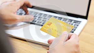 Man hand holding credit card for shopping online by laptop computer