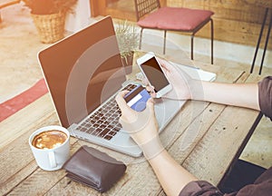 Man hand holding credit card use laptop and mobile phone vintage tone