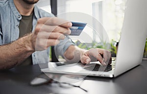Man hand holding credit card and using laptop in office, Businessman or entrepreneur working on computer, Online shopping concept