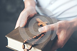 Man hand holding  cross with Bible