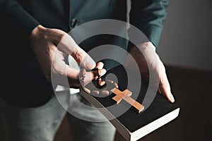 man hand holding cross with Bible.