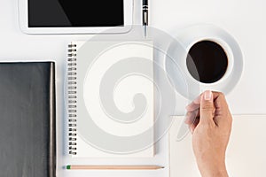 Man hand holding Cup of hot coffee tablte phone and notebook on