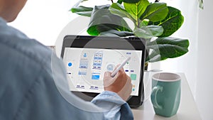 Man hand holding digital tablet with mobile app development prototype while working at home